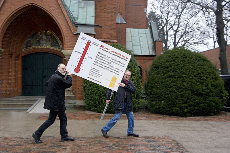 Zwei Männer halten ein großes Plakat