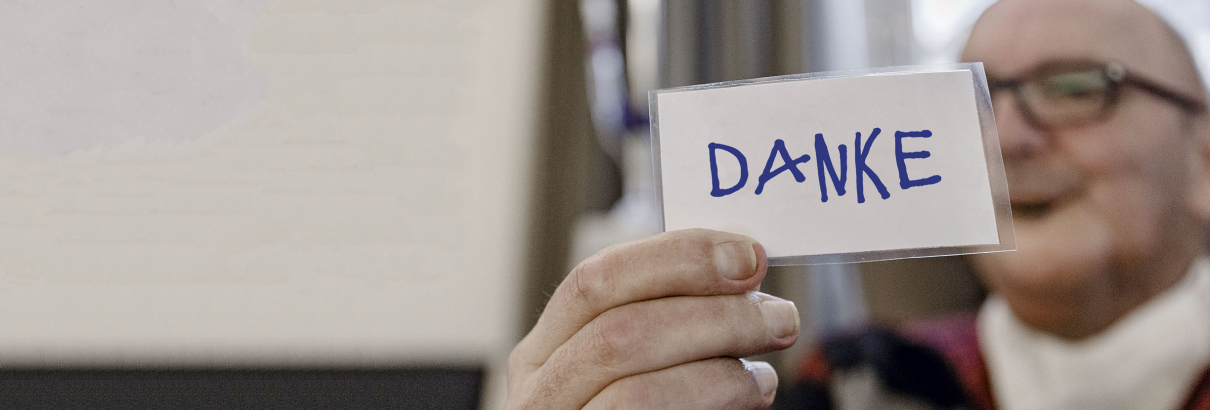 Ein Mann zeigt eine Karte auf der das Wort Danke steht